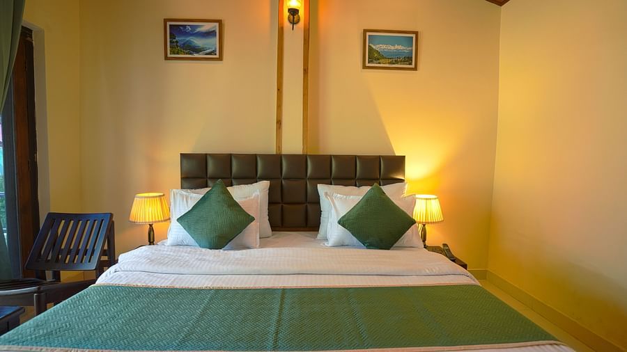 A proportionately set bed with cushions and table lamps on each side, with wall handings